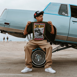 Male model pinching shirt beside classic lowrider car