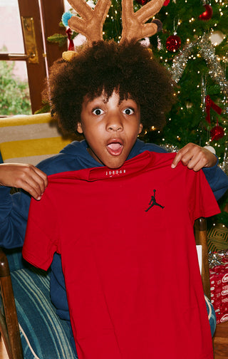 Kid model with red Jordan shirt as gift