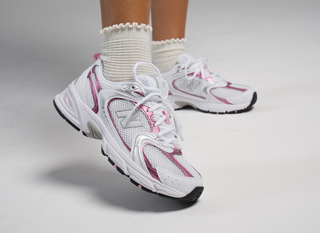 White and pink New Balance running shoes worn with white crew socks on a white background