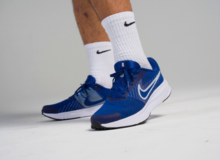 Blue Nike men walking shoes with white sole worn by a person standing on a white background