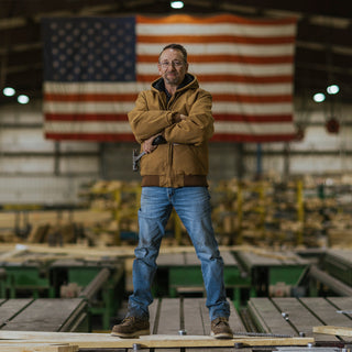 Brown denim sherpa jacket on man with button front, standing with arms crossed