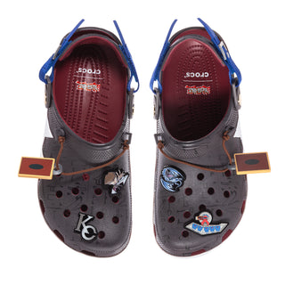 Pair of gray clogs with blue straps, burgundy interior, and decorative charms