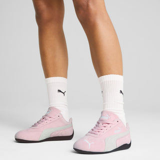 Pink Puma lace-up sneakers on white socks with black rubber outsole