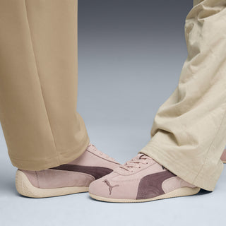 Mauve lace-up sneakers on feet with light trousers, Puma side logo visible