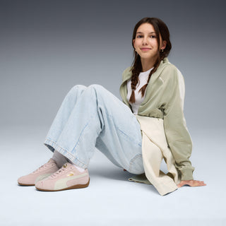 Youth sneakers worn with jeans, mauve-and-white low-top with PUMA logo and gum sole