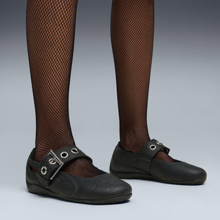 Black ballet flats with metal buckle strap on legs wearing fishnet tights