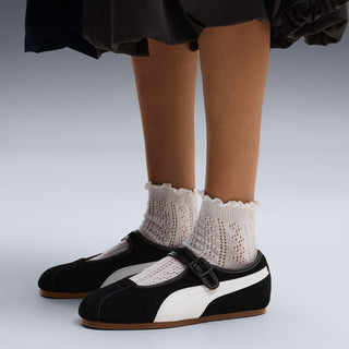Women's black suede Mary Jane shoes with white stripe worn with white knit socks