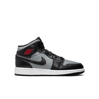 Youth mid-top sneakers in black with gray panels, white sole, and red accent logo