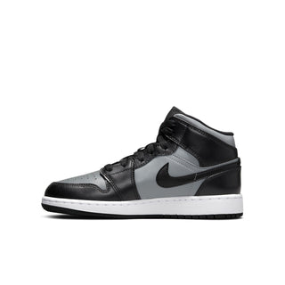 Youth mid-top sneakers side view in black and gray with white sole and red accent detail