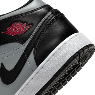 Youth mid-top sneaker close-up of side: black and gray with swoosh, red logo, white sole edge