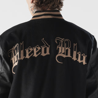 Men's black varsity jacket back with large arched 'Bleed Blue' lettering in gold tone.
