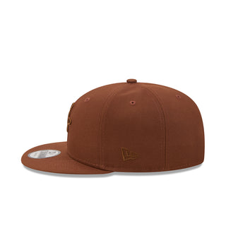 Brown baseball cap with small front emblem patch and curved brim
