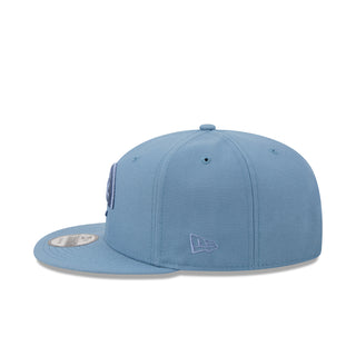 Faded blue baseball cap with small side logo patch and curved brim