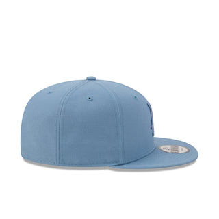 Faded blue snapback baseball cap, side view with embroidered details and flat brim