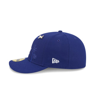 Blue baseball cap with bird pin, New Era side logo, and palm-tree embroidery.