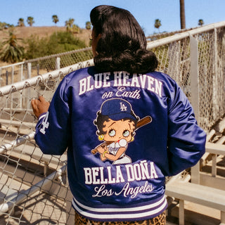 Royal blue womens varsity jacket back with large cartoon graphic and text, striped rib hem