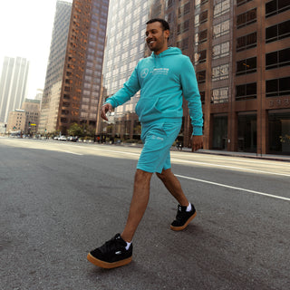 Men's teal athletic shorts with embroidered racing logos on the front