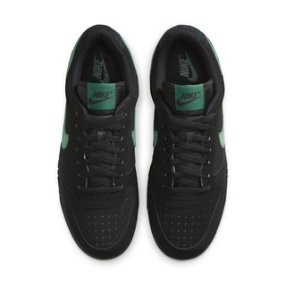 Black Nike sneakers with lace-up front and green NIKE tongue label.