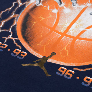 Close-up of orange basketball, lightning, and Jumpman graphic on navy T-shirt