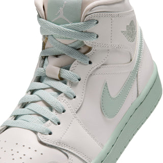 Close-up of women's mid-top sneaker upper: mint laces, swoosh, and stitching