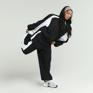 Women’s black wind pants with white side stripes and relaxed fit
