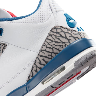 Youth white sneaker close-up with blue mudguard, elephant-print panel, and air window