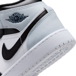 Close-up of white leather mid-top youth sneaker with Air logo patch and lace tab detail