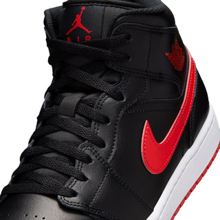 Close-up of black mid-top sneakers with red Swoosh, laces, and Air Jordan logo