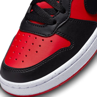 Close-up of youth red and black sneaker toe with perforations, lace eyelets, and white sole.