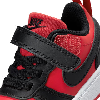 Close-up: toddler sneaker side with red upper, black hook strap, and white midsole