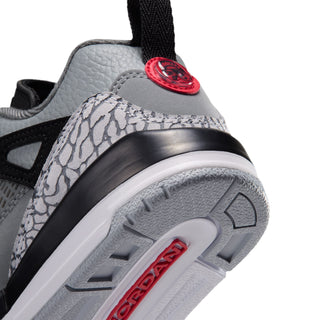 Kids' sneaker close-up of toe: black-and-gray midsole with red accent badge and traction.
