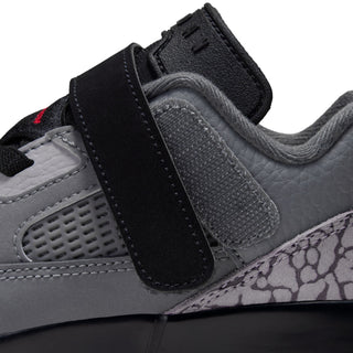Kids' sneaker side close-up: black strap over textured gray panel and speckled toe trim.