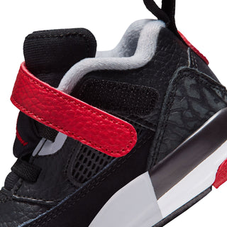 Close-up of toddler sneaker side: red strap, black textured panel, and white midsole