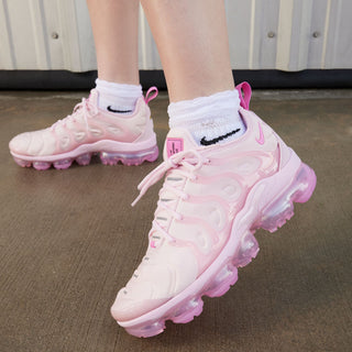 Close view of woman’s pink lace-up sneakers with translucent outsole and swoosh detail