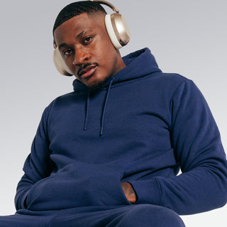 Man wearing a blue hoodie and headphones on a light gray background