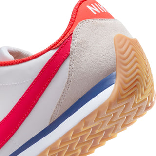 Women's sneaker side close-up showing red trim, blue stripe, and gum rubber outsole