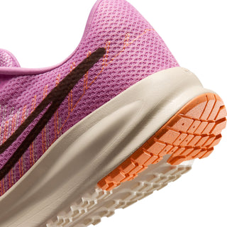 Close-up of pink shoe side with cream midsole and orange traction outsole