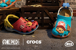 Two children's shoes, one red and one blue, with cartoon characters on a dark surface. Crocs logo is visible.