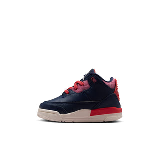 Toddler sneaker side profile with navy leather, red laces, and beige outsole