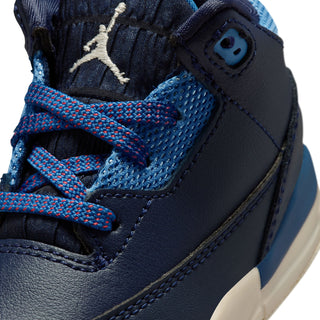 Close-up of toddler sneaker: navy leather, mesh detail, and red/blue braided laces
