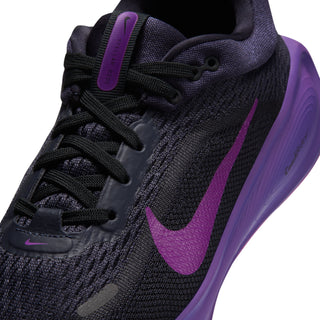 Close-up of youth running shoe mesh, black laces, purple swoosh, and padded sole
