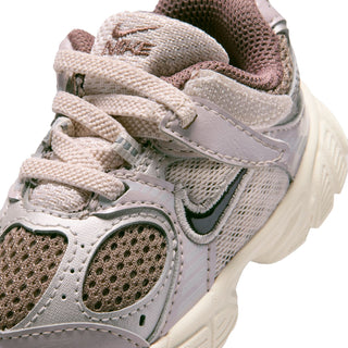 Toddler Nike sneaker close-up showing stitched overlays, laces, and green swoosh