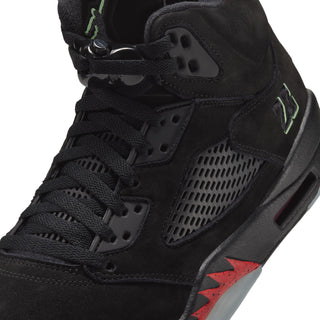 Black high-top sneaker close-up with lace eyelets, mesh panel, and green logo