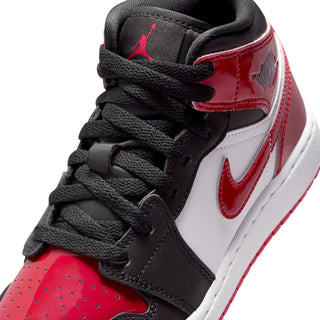 Close-up of youth sneaker upper: black overlays, white panels, red toe and Nike swoosh