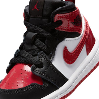 Kids mid-top sneaker close-up of black laces and red Nike Swoosh on white panel