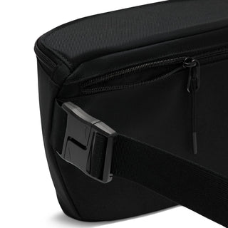 Black waist pack close-up: textured fabric with zipper track and pull tab.