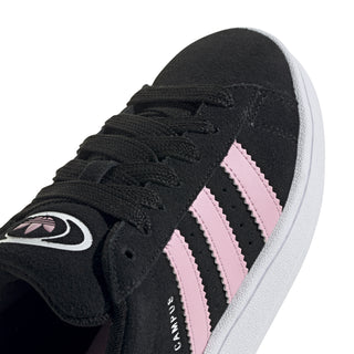 Close-up of black lace-up sneakers with pink triple stripes and adidas logo patch.