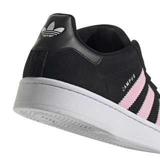 Side view of black suede sneakers with pink stripe accent, white midsole and collar.