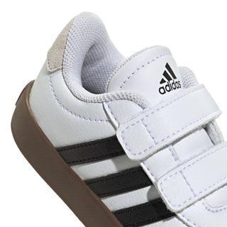 Toddler white sneaker upper close-up with adidas logo and hook-and-loop strap, gum edge.