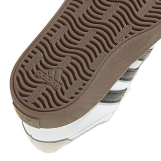 Toddler sneaker outsole close-up with adidas logo and wavy tread, brown rubber.